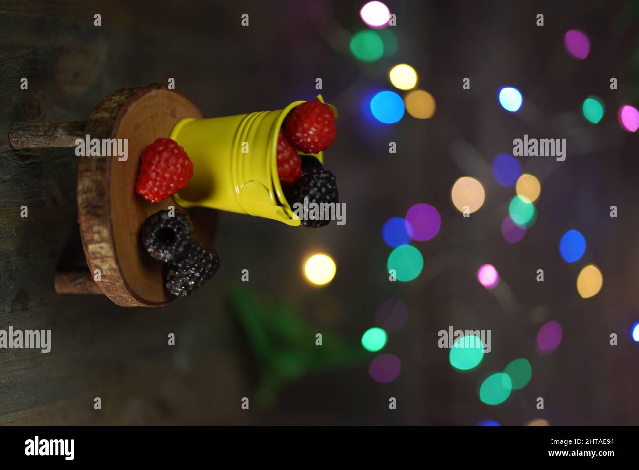 Ein dekorativer Eimer mit Beeren und Bokeh-Lichtern auf dem Hintergrund Stockfoto