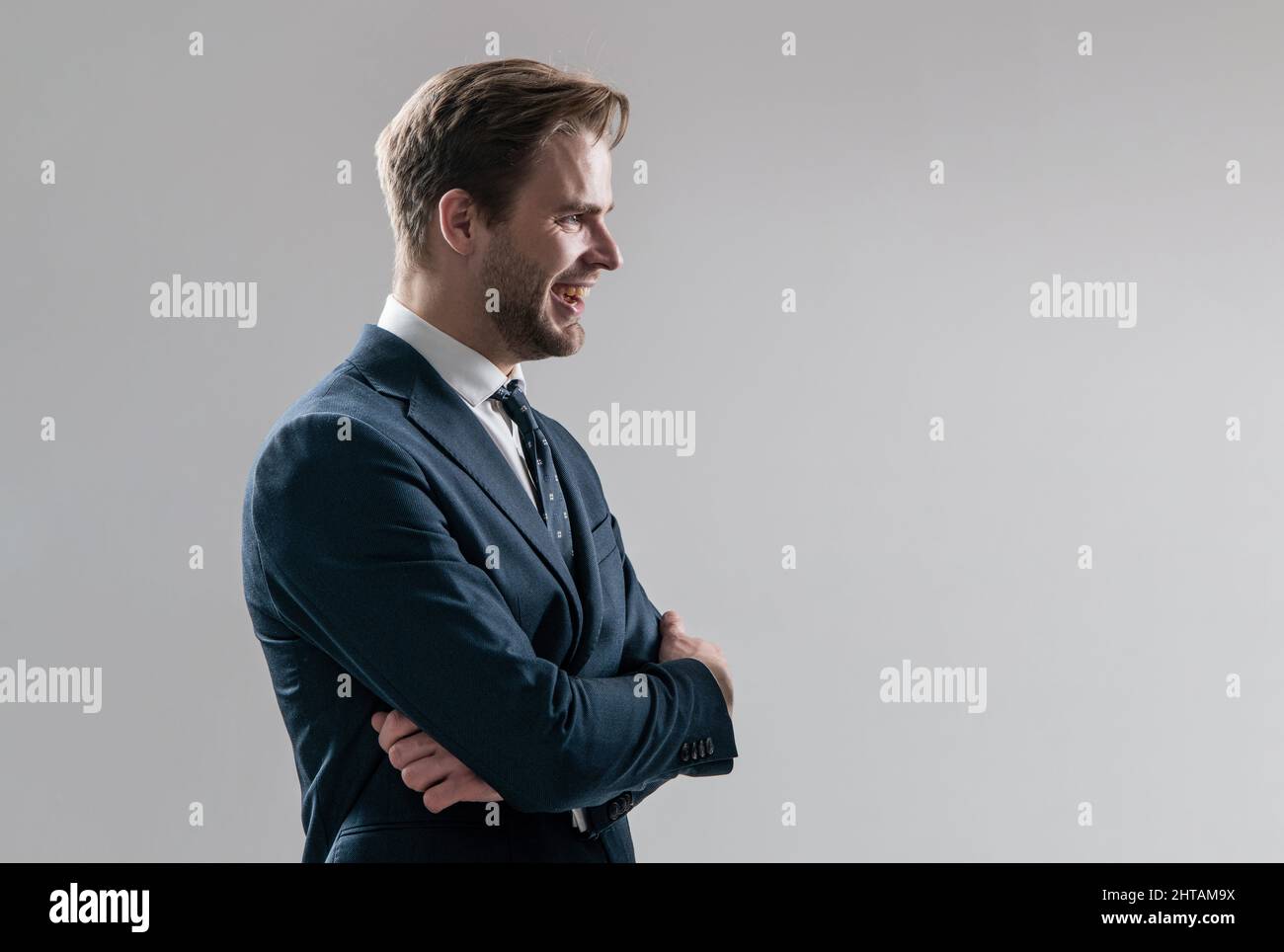 Ein glücklicher, selbstbewusster Mitarbeiter steht seitlich und hält die Arme gekreuzt, Selbstvertrauen Stockfoto