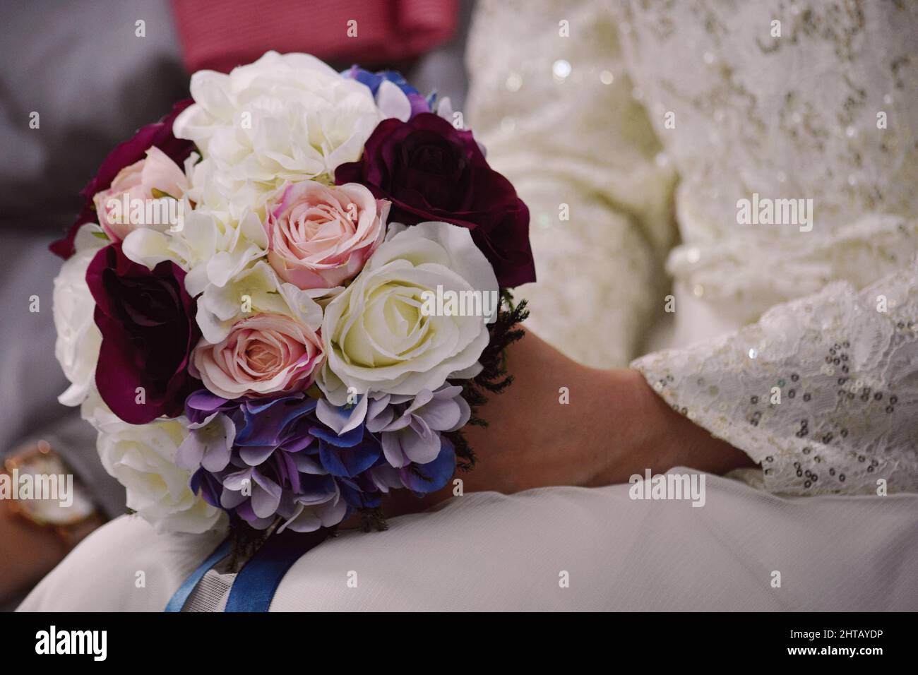 Eine selektive Fokusaufnahme eines bunten Straußes in den Händen der Braut Stockfoto