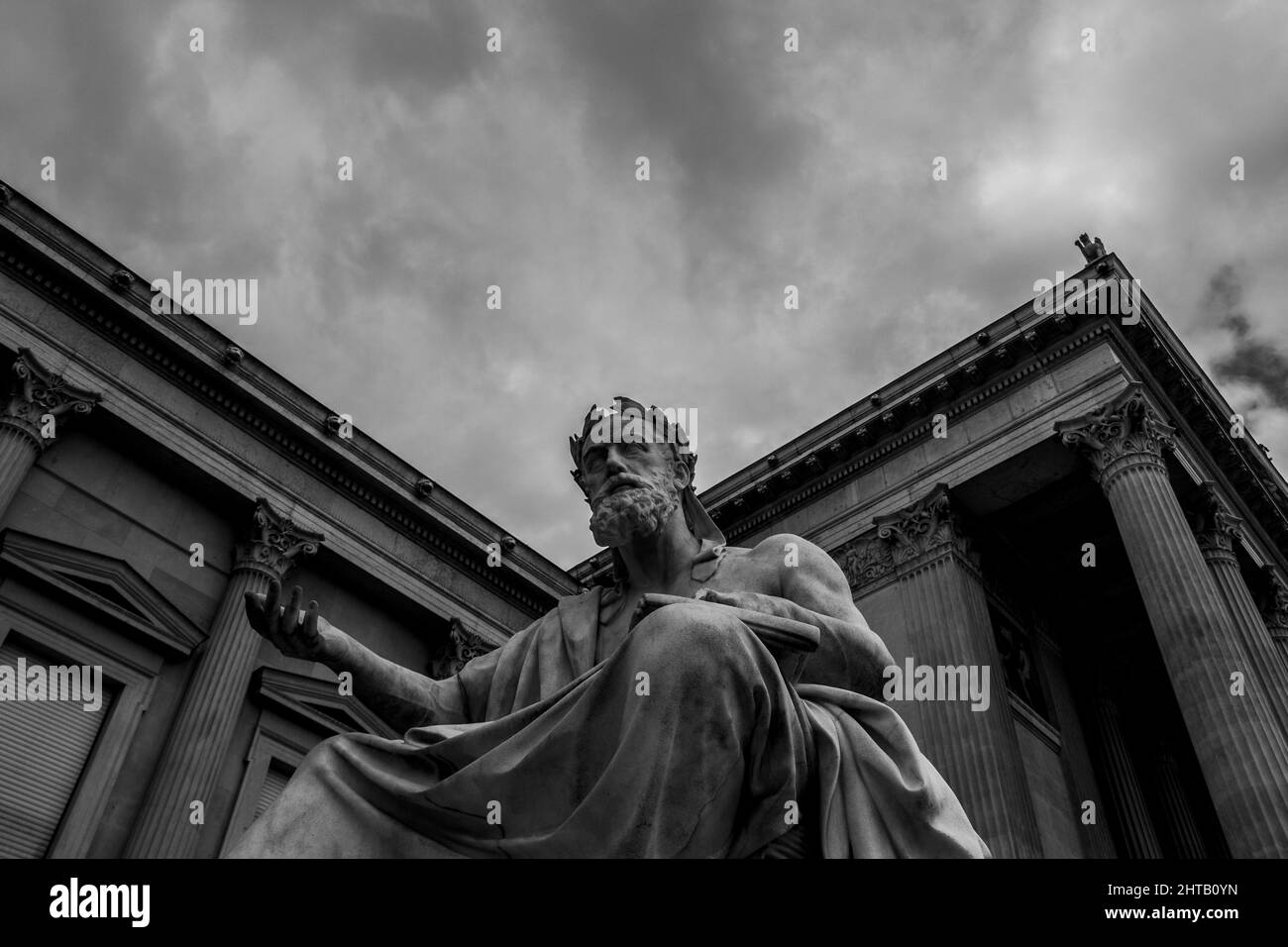 Low-Angle-Aufnahme der Statue eines Akademikers gegen ein römisches Architekturgebäude Stockfoto