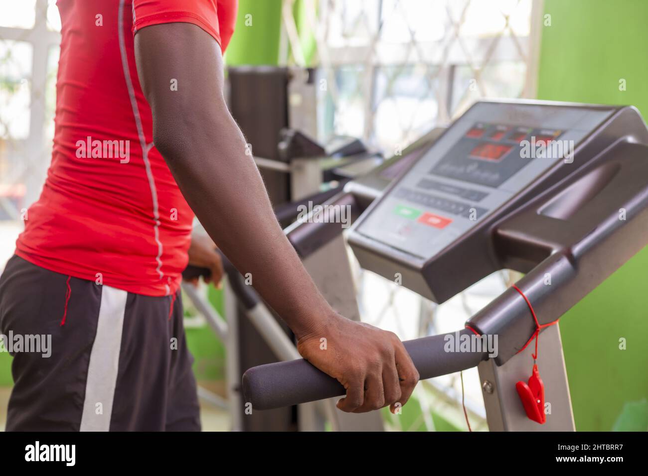 Junger, sportlicher afrikanischer Mann, der in einem Fitnessstudio auf einem Laufband läuft Stockfoto