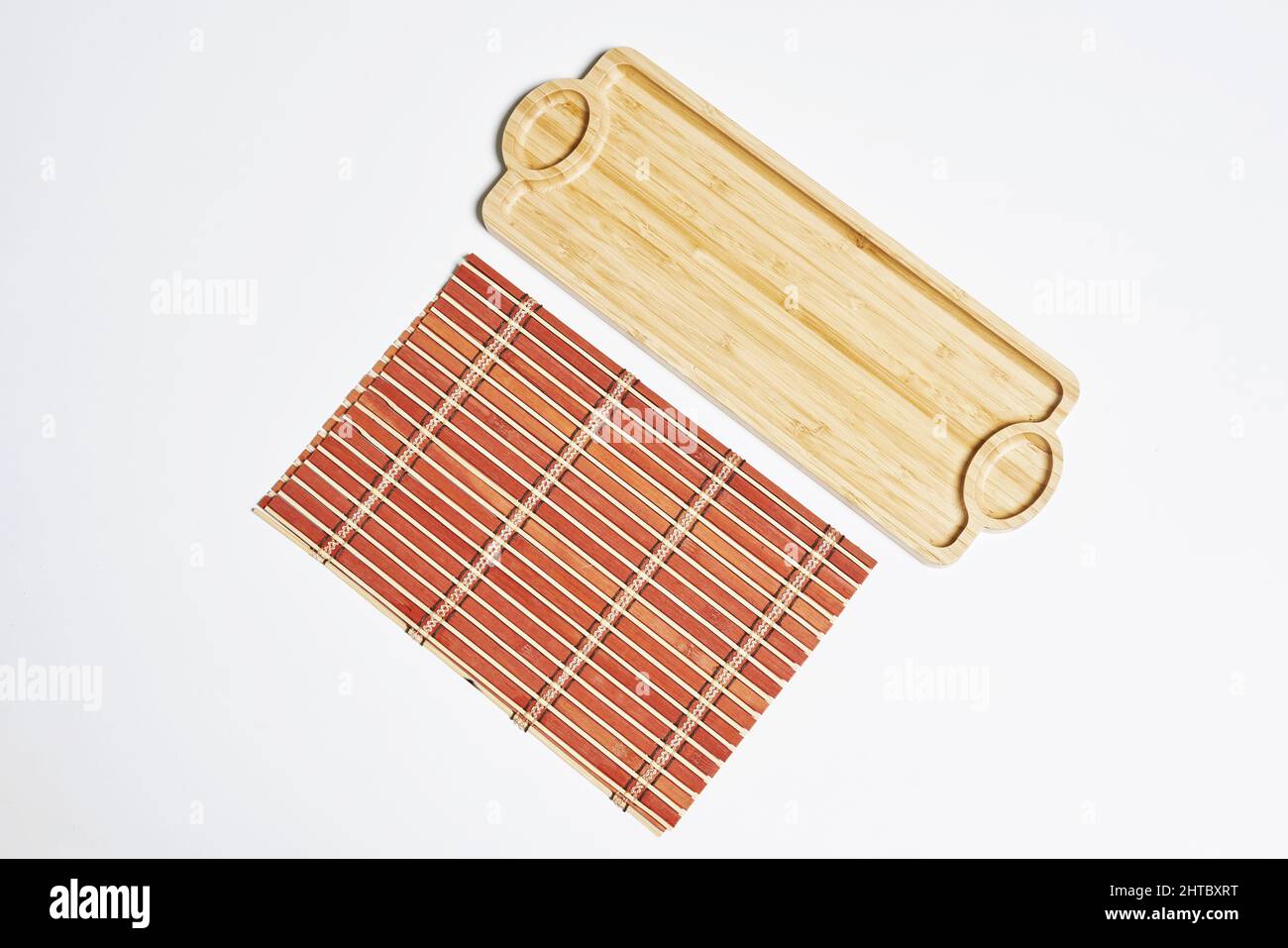 Draufsicht auf Bambususususususususrollmatte und ein Holztablett isoliert auf weißem Hintergrund Stockfoto