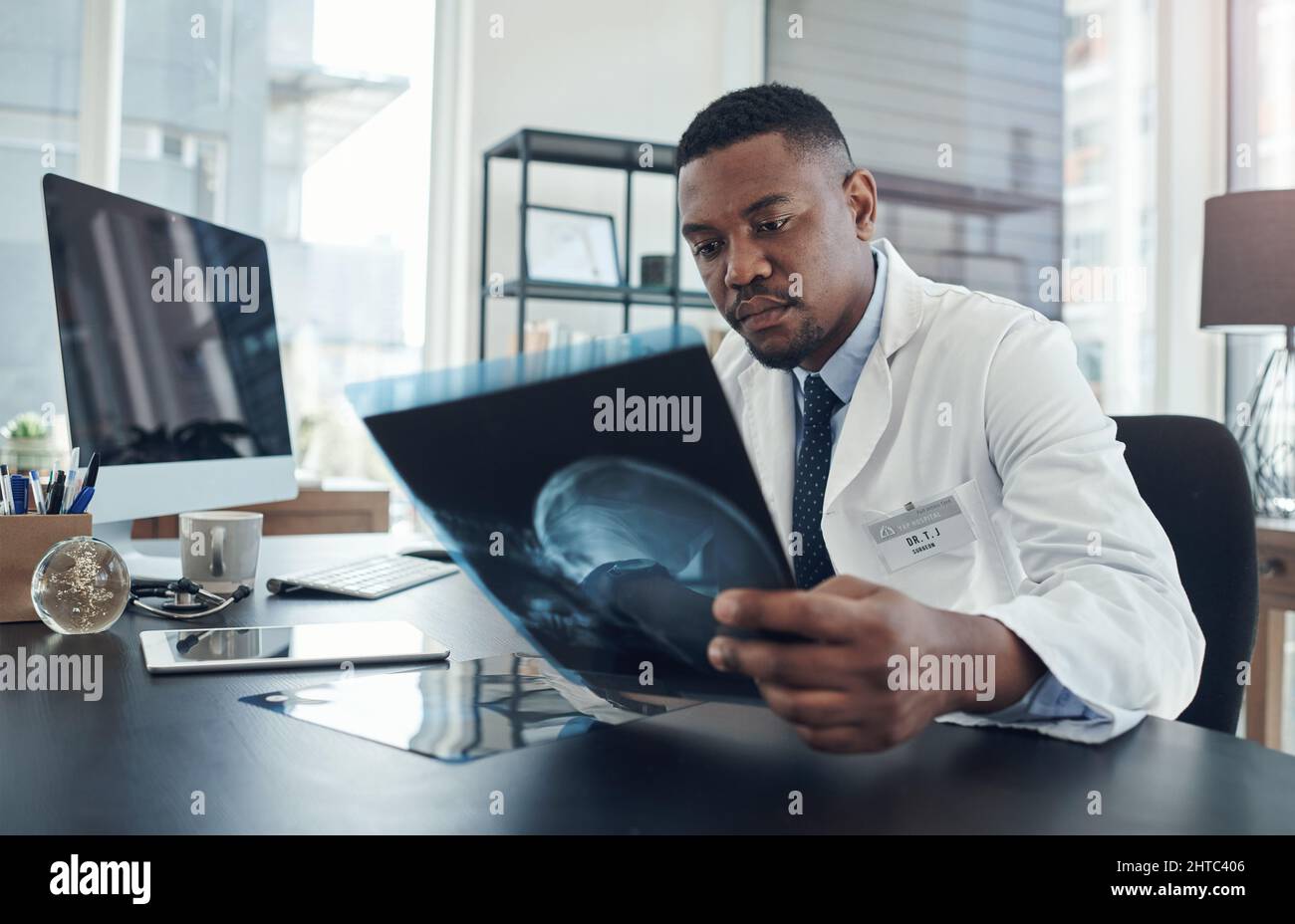 Untersuchung dieser Untersuchung auf Verletzungen. Aufnahme eines jungen Arztes, der eine Röntgenaufnahme in einem Büro untersucht. Stockfoto
