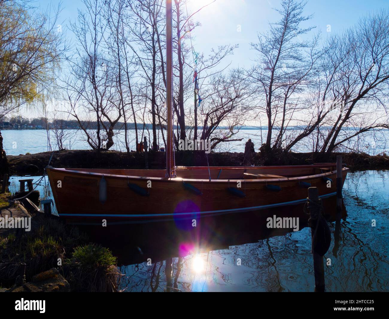 Segelboot aus Holz, das bei Sonnenuntergang am Ufer festgemacht wurde Stockfoto