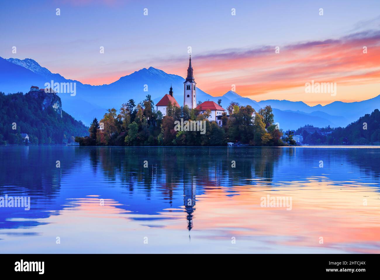 Bleder See, Slowenien. Sonnenaufgang am Bleder See mit der berühmten Insel Bled und dem historischen Schloss Bled im Hintergrund. Stockfoto