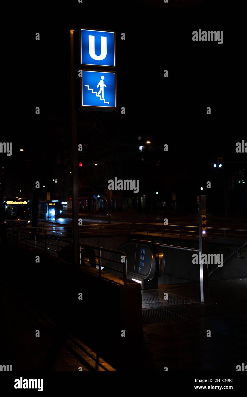 Eine vertikale Aufnahme des U-Bahnhofes mit dem Symbol für die Treppe in München, Deutschland, während der Nacht Stockfoto