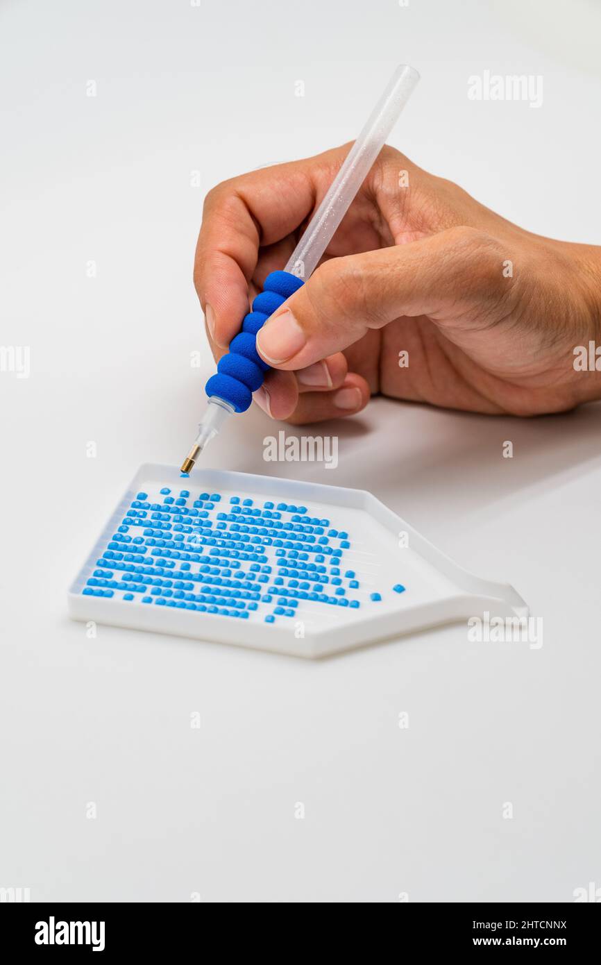 Diamant Malerei Hand Stift Kommissionierung Acryl Strass aus Tablett auf weißem Hintergrund. Stockfoto