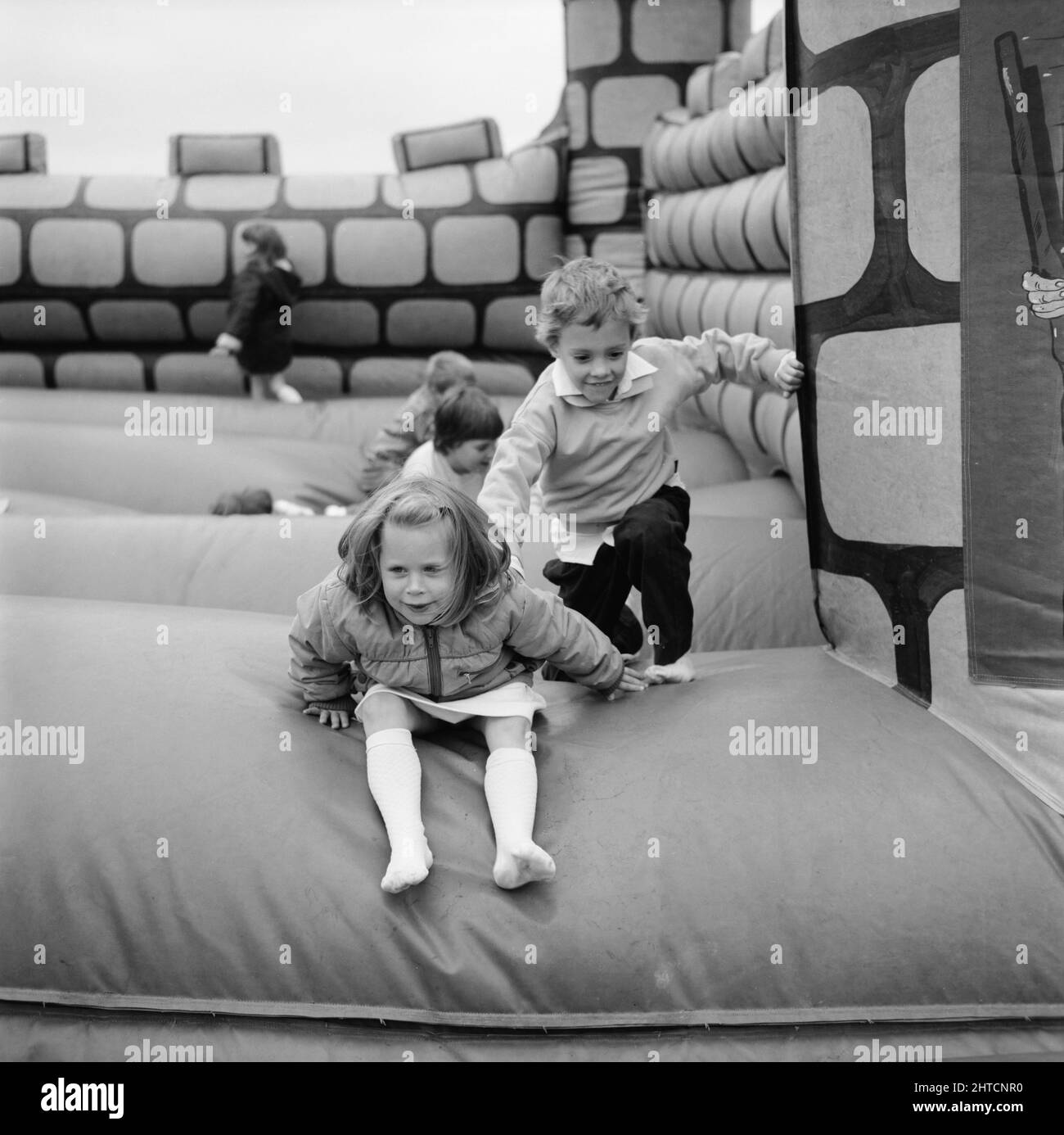 Laing Sports Ground, Rowley Lane, Elstree, Barnett, London, 11/06/1988. Kinder spielen auf der Hüpfburg beim Familientag 1988 auf dem Laing's Sports Ground. Zu den Attraktionen des diesjährigen Familientages gehörten eine Parade mit Oldtimern, Hubschrauberflüge, Plattenschlagen, Stände, ein Wettbewerb im Stil „IT's a Knockout“ sowie Tennis- und Fußballturniere mit sechs Spielern. Eröffnet wurde die Veranstaltung von John Conteh, dem ehemaligen Weltmeister im Leichtgewicht, und endete mit einem Barbecue und einer Disco. Stockfoto
