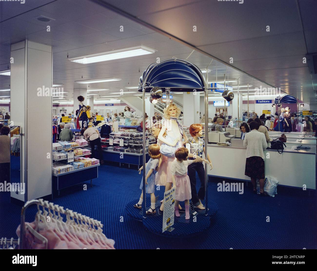 Queensgate Centre, Peterborough, Cambridgeshire, 19/04/1982. Innenansicht der British Home Stores im Queensgate Shopping Centre, mit Kleidung auf Schaufensterpuppen. Der Auftrag für das Queensgate Center im Herzen von Peterborough wurde 1975 an Laing vergeben. Verschiedene Planungsanfragen und Designänderungen verzögerten den Beginn der Arbeiten, doch die Einweihungsfeier fand schließlich im April 1978 statt. Das mehrstufige Einkaufszentrum wurde mit einem großen Parkplatz und einer neuen Bushaltestelle sowie vielen bekannten Einzelhändlern wie John Lewis, British Home Stores und Little entworfen Stockfoto