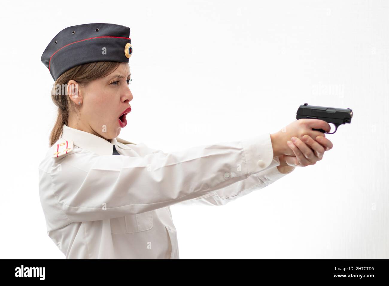 Eine schöne junge Frau russischen Polizist Oberstleutnant in Uniform in einer Mütze mit einer Pistole in den Händen auf einem weißen Hintergrund. Selektiv Stockfoto