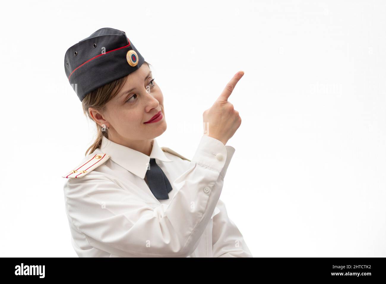 Schöne junge weibliche russische Polizist in Kleideruniform zeigt Schilder mit ihren Händen auf weißem Hintergrund. Selektiver Fokus. Hochformat Stockfoto