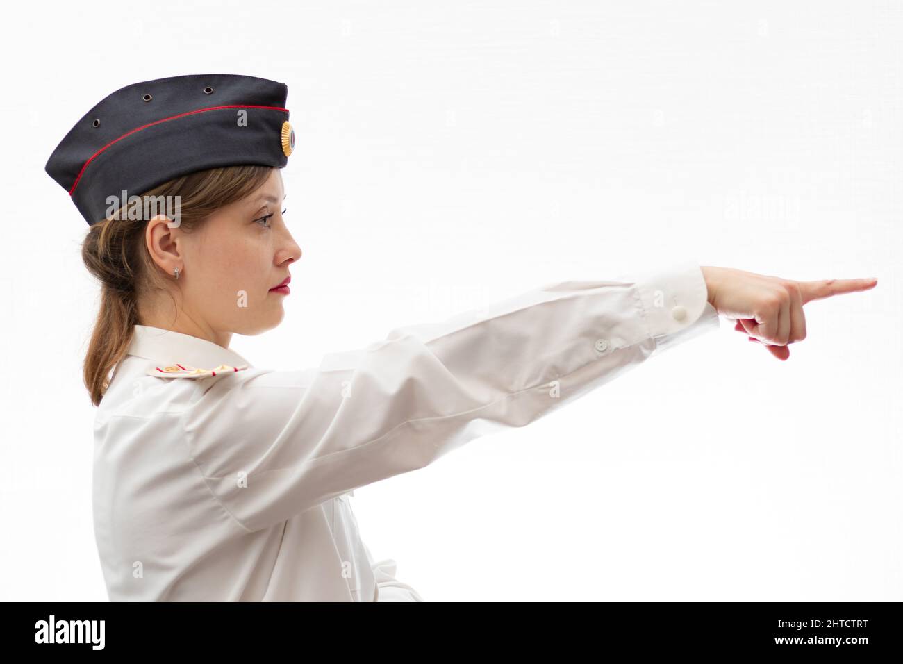 Schöne junge weibliche russische Polizist in Kleideruniform zeigt Schilder mit ihren Händen auf weißem Hintergrund. Selektiver Fokus. Hochformat Stockfoto