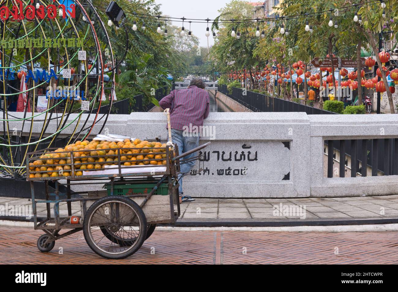 Ein orangefarbener Händler in Saphan Han (Brücke) blickt auf Klong (Kanal) Ong Ang, im Zentrum der Ong Ang Walking Street, einem beliebten Wochenend-Straßenmarkt Stockfoto