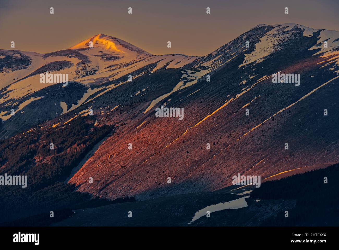 Goldene Lichter bei Sonnenuntergang auf den schneebedeckten Gipfeln der Abruzzen. Wolkiger Himmel. Roccaraso, Provinz L'Aquila, Abruzzen, Italien, Europa Stockfoto