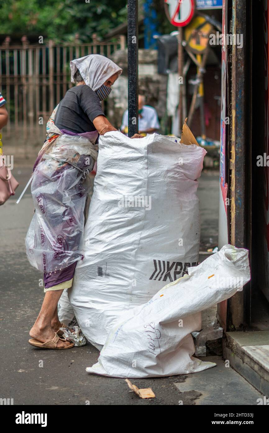 Eine vertikale Aufnahme einer armen alten Dame, die in Mumbai, Indien, Plastik im Müllbeutel findet Stockfoto