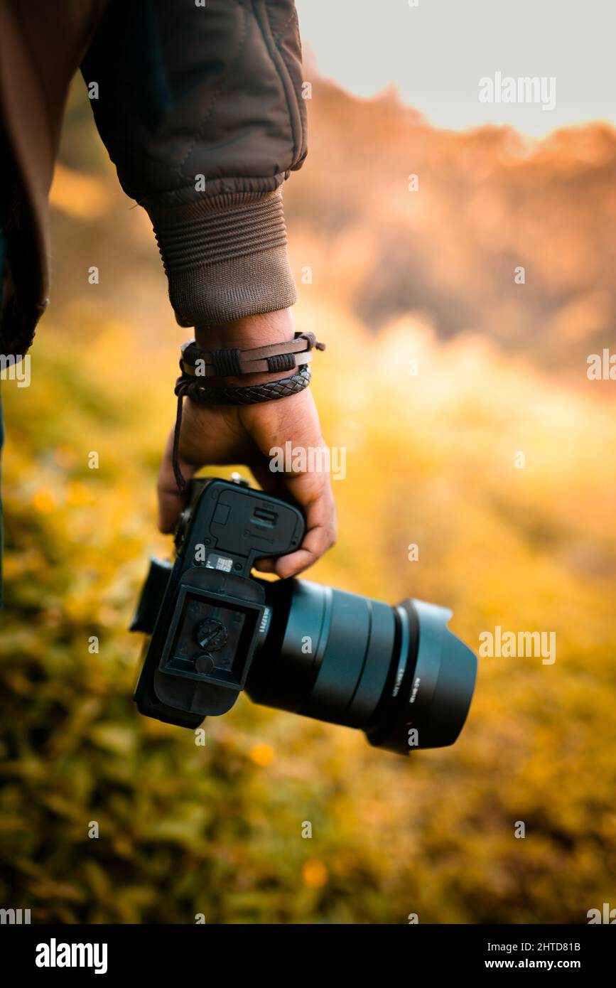 Der Fotograf hält eine Kamera, eine DSLR-Kamera mit unscharfem Hintergrundbild mit selektivem Fokus Stockfoto