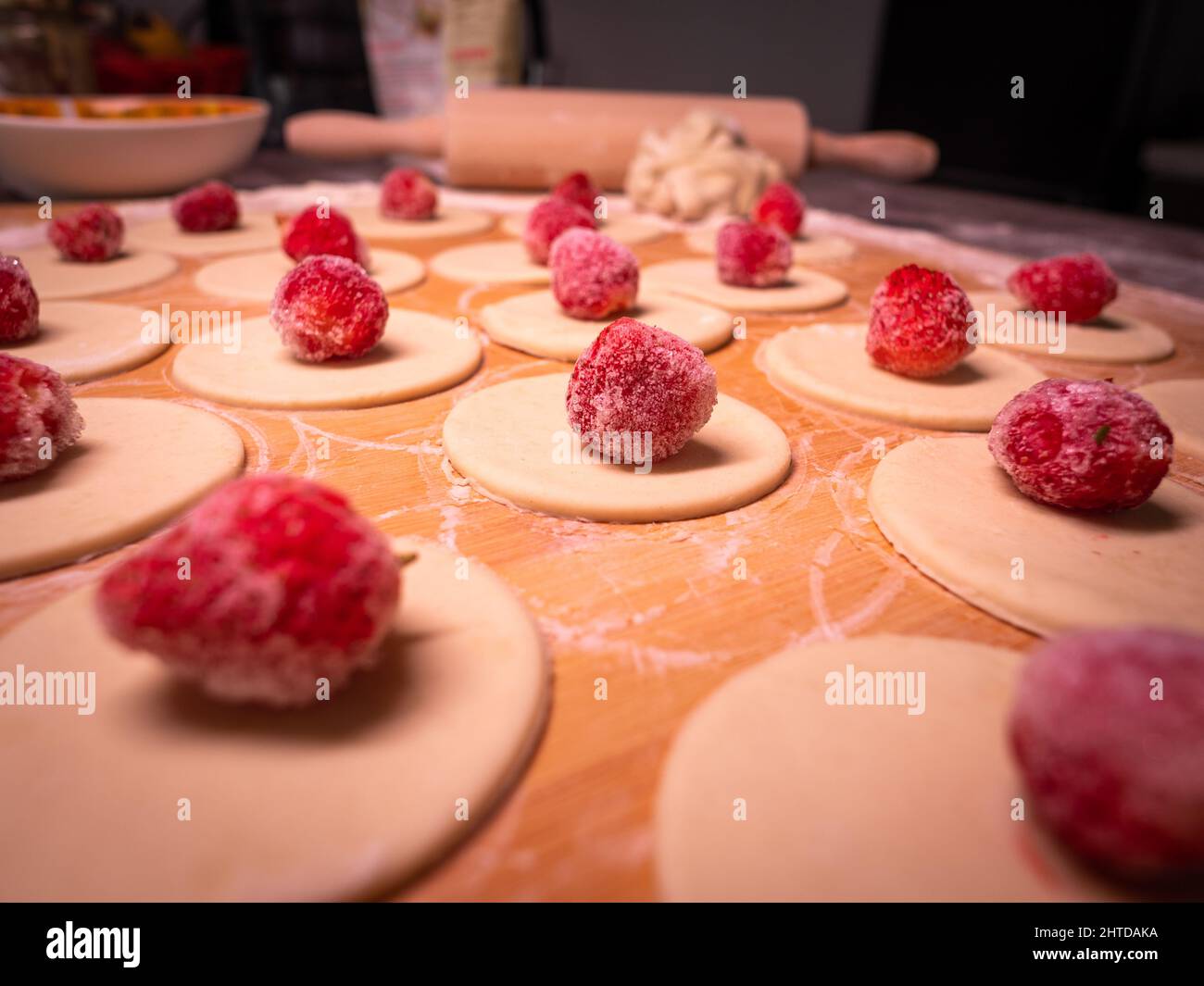 Knödel Teig mit Erdbeeren, schneiden Stücke von Teig und Erdbeerfrucht warten auf Verpackung kleben Stockfoto