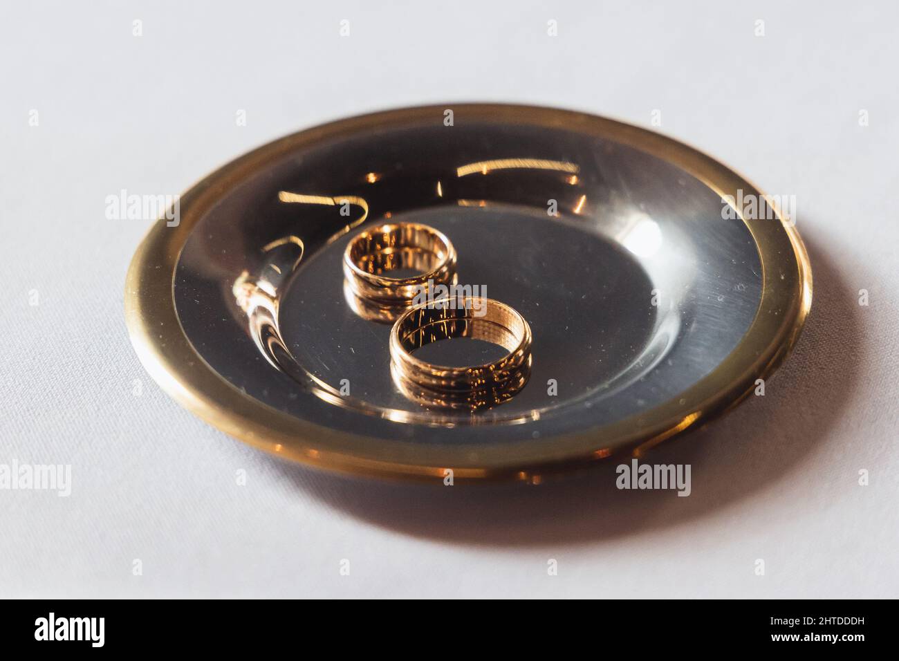 Zwei goldene Eheringe auf einer Metallplatte Stockfoto