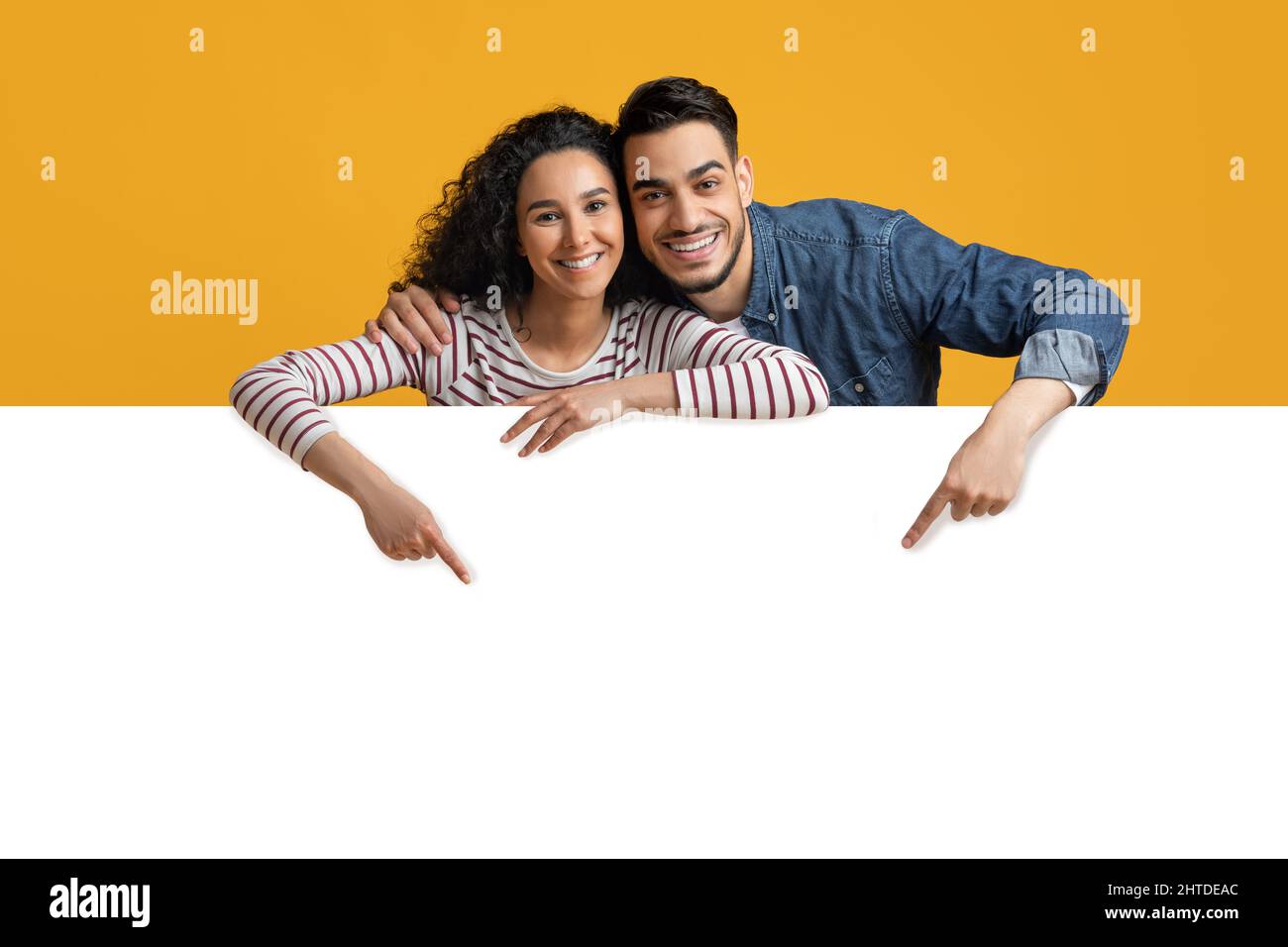 Glückliches Junges Arabisches Paar Zeigt Nach Unten Auf Big White Advertisement Board Stockfoto