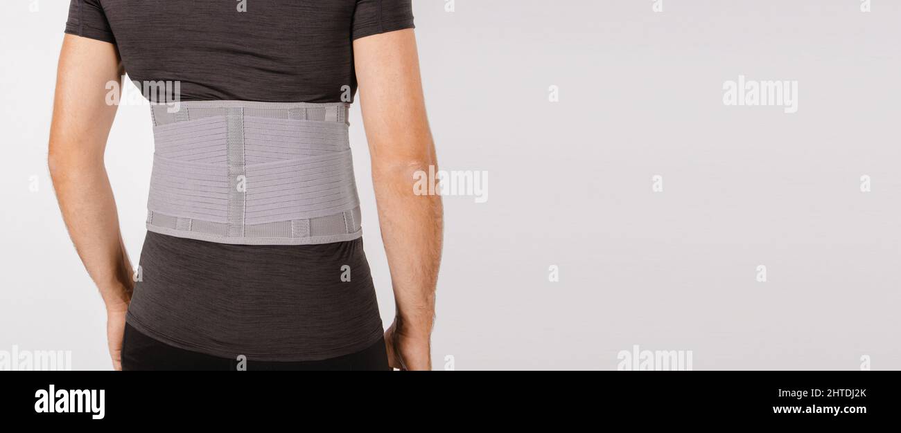 Lendenwirbelstütze am menschlichen Körper isoliert auf weißem Hintergrund. Trauma des Rückens. Rückenstütze, orthopädische Lendenwirbelstütze, Stützgurt für die Rückenmuskulatur. Senken Stockfoto
