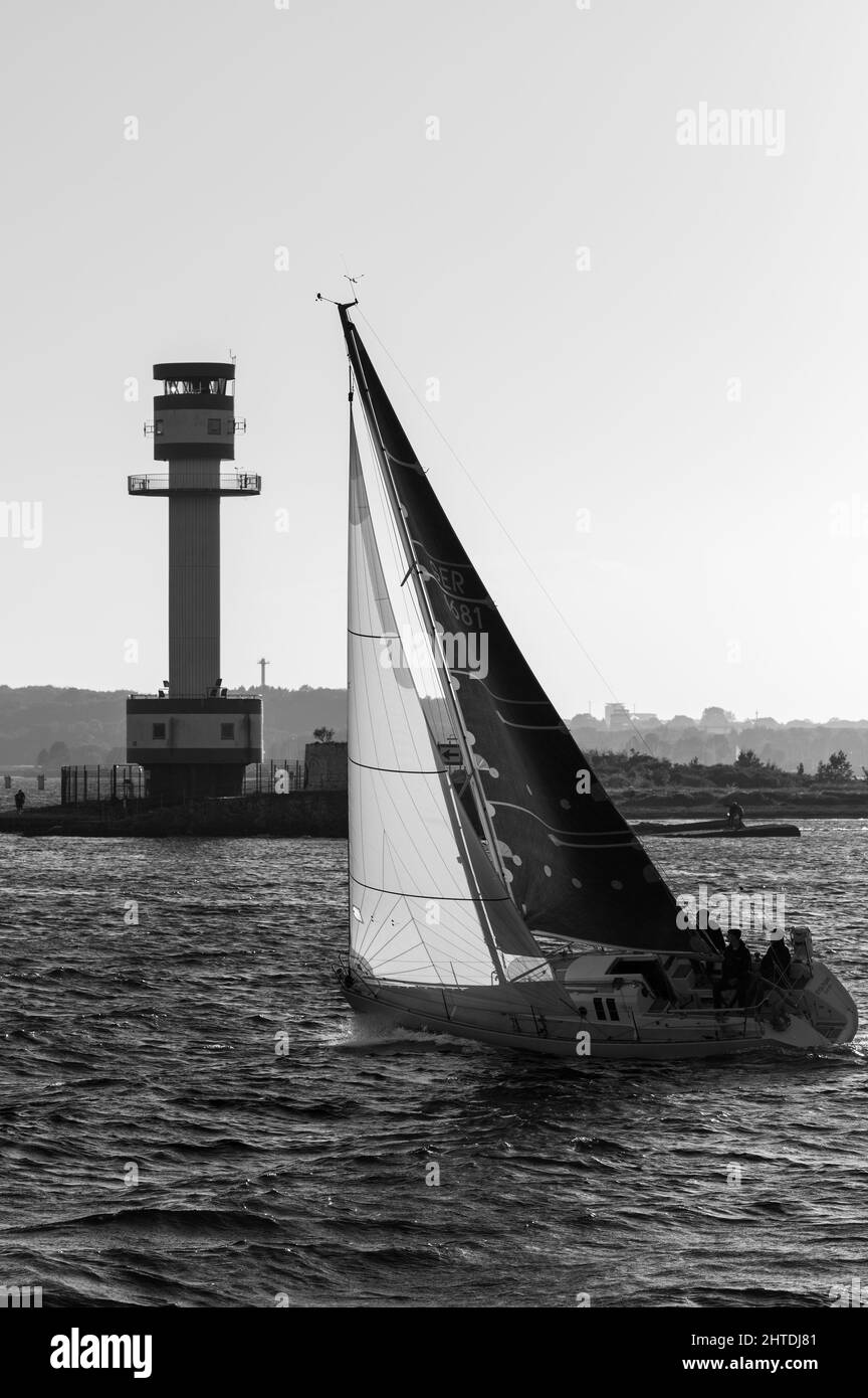 Graustufenaufnahme eines Segelbootes in der Nähe eines Leuchtturms an der Ostsee. Kiel, Deutschland Stockfoto