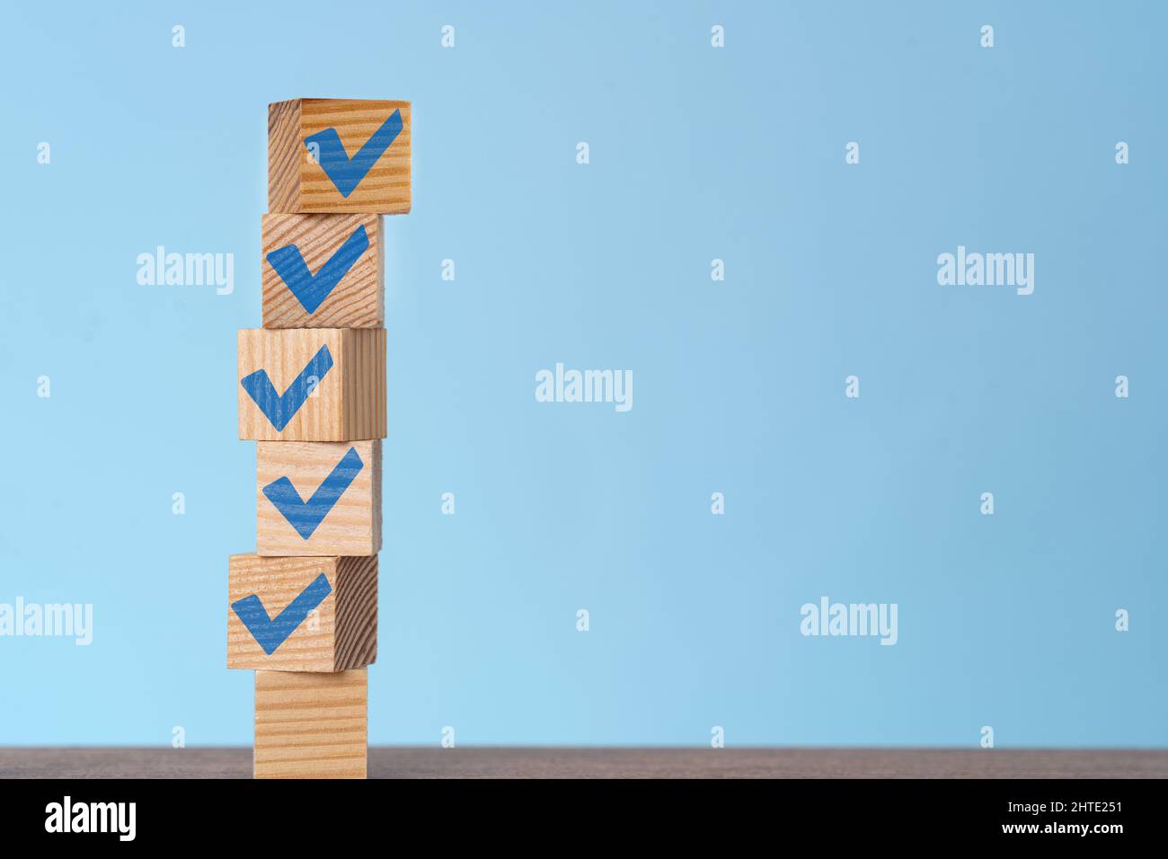 Gestapelte Holzwürfel mit blauem Quader. Konzept von Checkliste, Ziel erreicht, Lösung und To-Do-Liste. Stockfoto