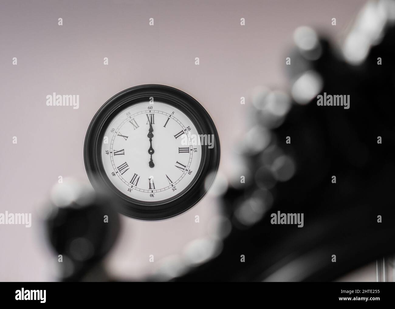 12:00 zwölf Uhr Zeit an der Wand mit selektivem kreativen Fokus. Große schwarze Wanduhr. Stockfoto