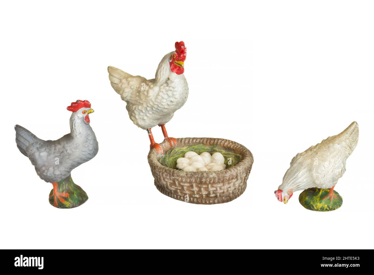 Drei alte Spielzeughühner mit Korb gefüllt mit Eiern isoliert auf weißem Hintergrund Stockfoto