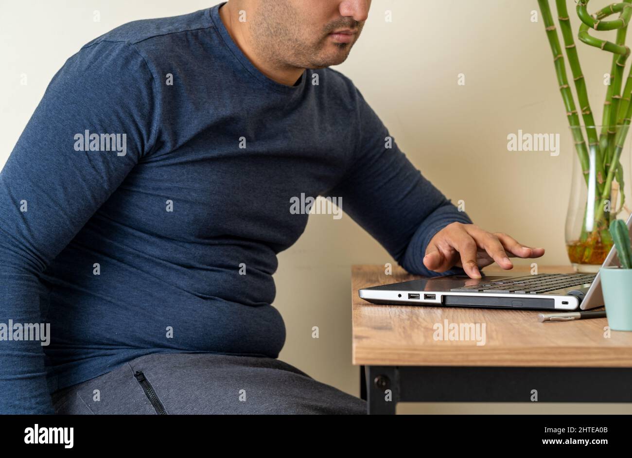 Seitenansicht Foto des Home Office-Mitarbeiters mit fettem Bauch. Konzept von Fett oder Adipositas aufgrund von Remote-Arbeit. Stockfoto
