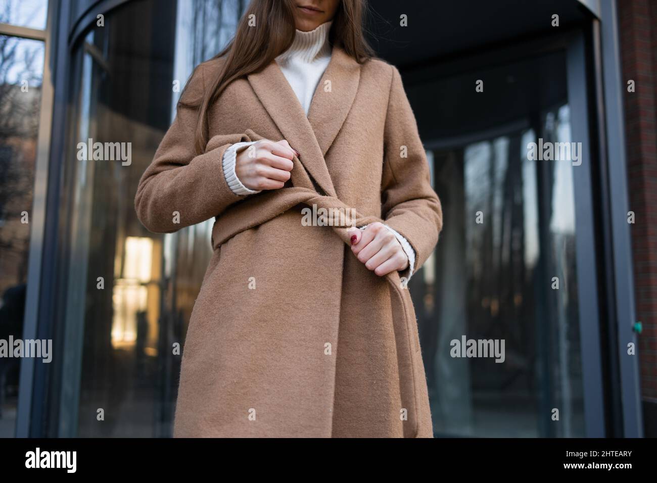 Mädchen bindet einen Gürtel auf einen Mantel Stockfoto