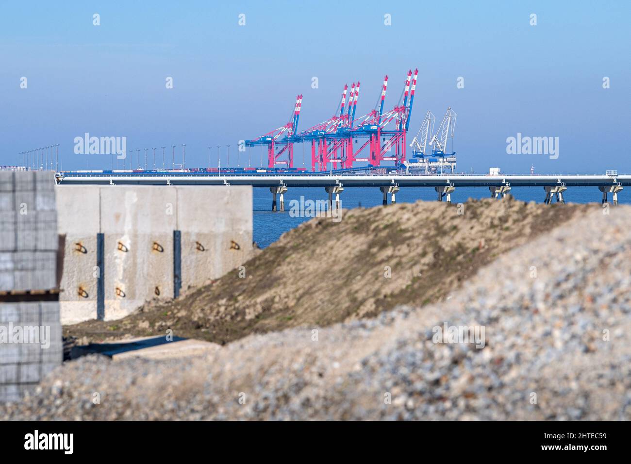 28. Februar 2022, Niedersachsen, Wilhelmshaven: Hinter einer Baustelle am Deich ist der Jade-Weser-Hafen zu sehen. Kanzler Scholz hatte als Reaktion auf den Ukraine-Krieg und die Abhängigkeit von russischem Erdgas den raschen Bau von zwei Terminals für Flüssigerdgas (LNG) in Deutschland angekündigt und Wilhelmshaven als Standort benannt. Der genaue Standort ist noch nicht bekannt. Foto: Sina Schuldt/dpa Stockfoto