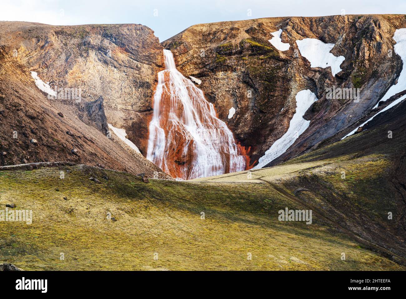 Blick auf uname Wasserfälle an der Klippe des schneebedeckten Berges in der Sommersaison im Hochland, Island. Stockfoto