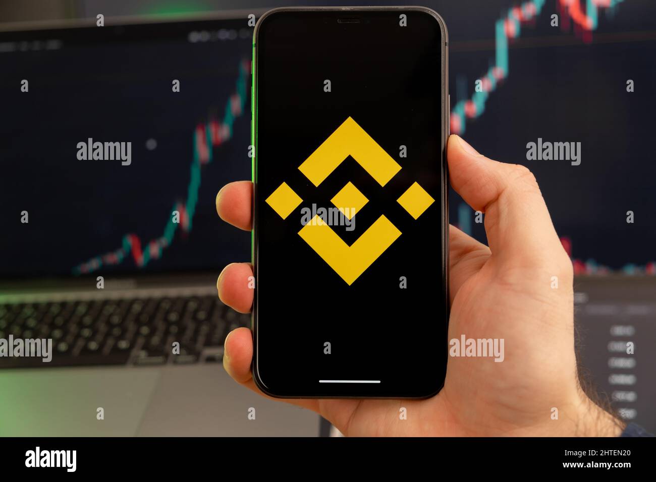 BNB-App zur Analyse der Kryptowährungsaktien auf dem Bildschirm des Mobiltelefons in Menschenhand und wachsender Charts, die im Hintergrund Handelsdaten enthalten, Februar 2022, San Francisco, USA. Stockfoto