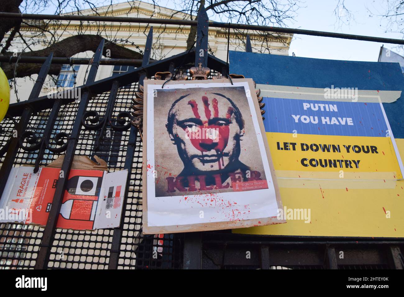 London, Großbritannien. 27.. Februar 2022. Auf dem Botschaftstor sieht man während des Protestes ein Plakat, das den russischen Präsidenten Wladimir Putin als "Mörder" bezeichnet.Demonstranten bedeckten die Eingangstore und die Wand der russischen Botschaft mit Plakaten, Schilder und Botschaften, die mit Kalk geschrieben wurden, während der Krieg in der Ukraine andauert. (Foto: Vuk Valcic/SOPA Images/Sipa USA) Quelle: SIPA USA/Alamy Live News Stockfoto