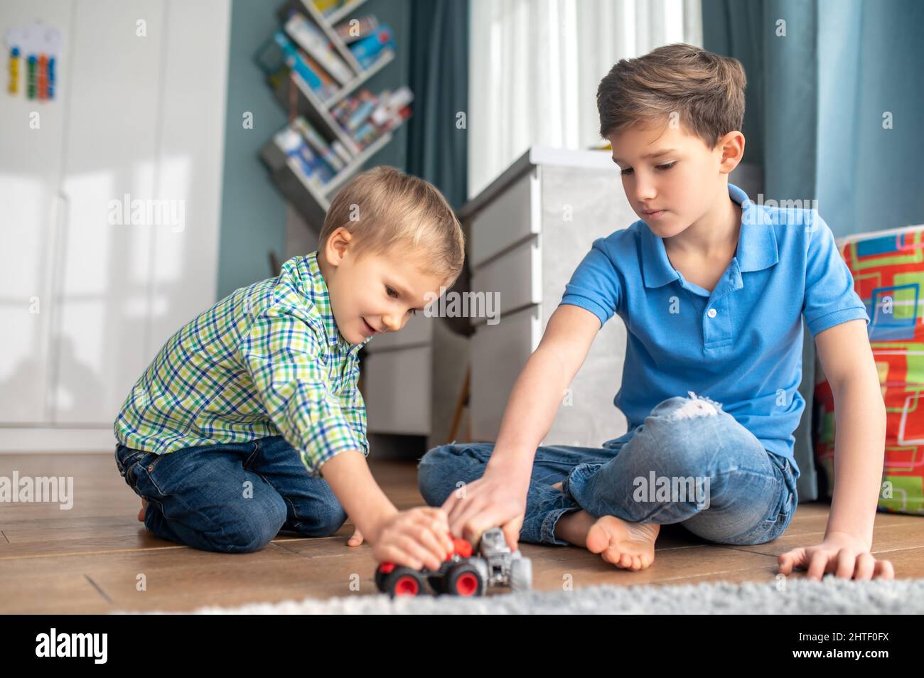 Zwei Kinder, die mit ihren Spielzeugfahrzeugen spielen Stockfoto