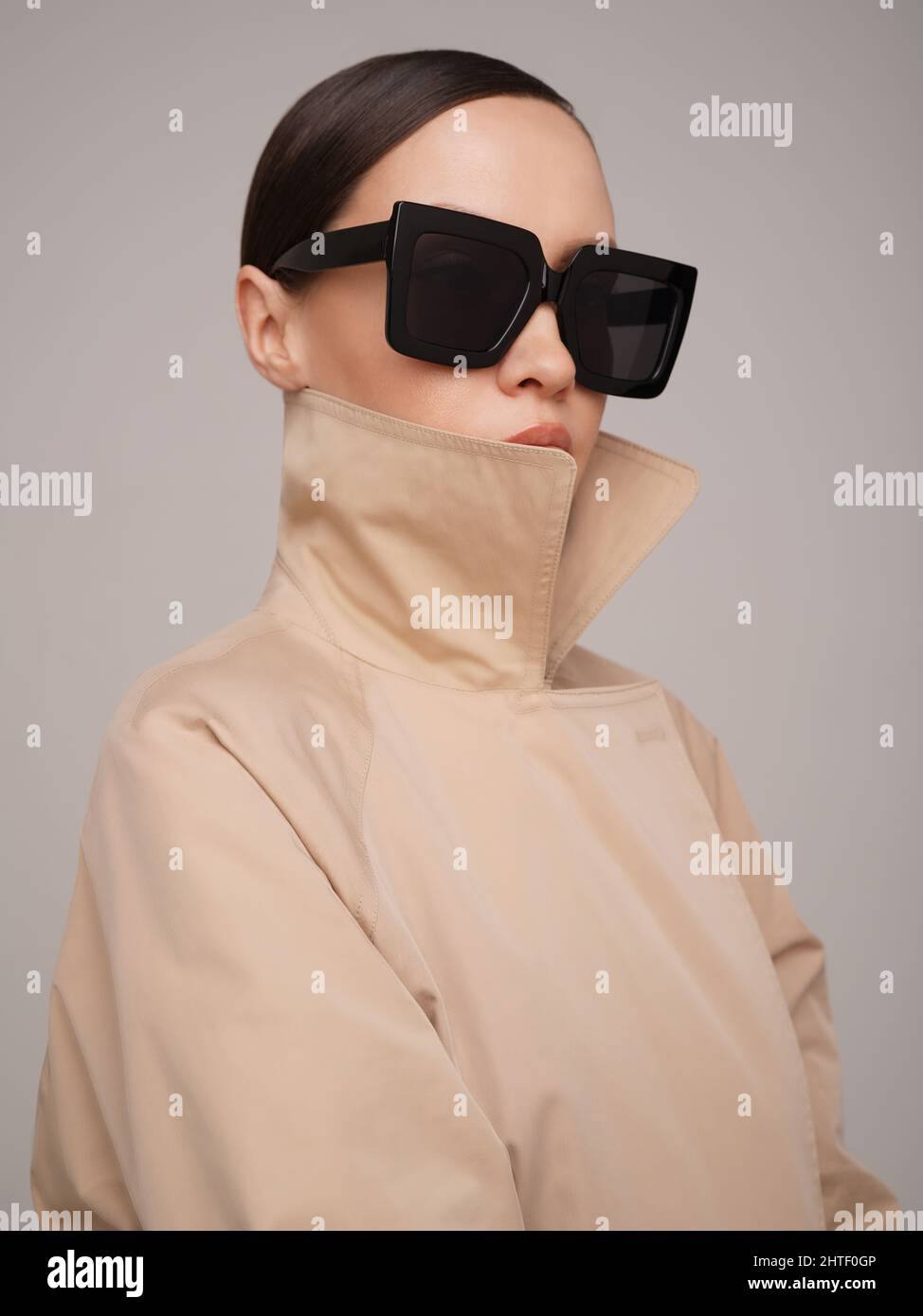 Schöne junge Dame in beigem Trenchcoat und schwarzer Sonnenbrille. Mode und Style Stockfoto