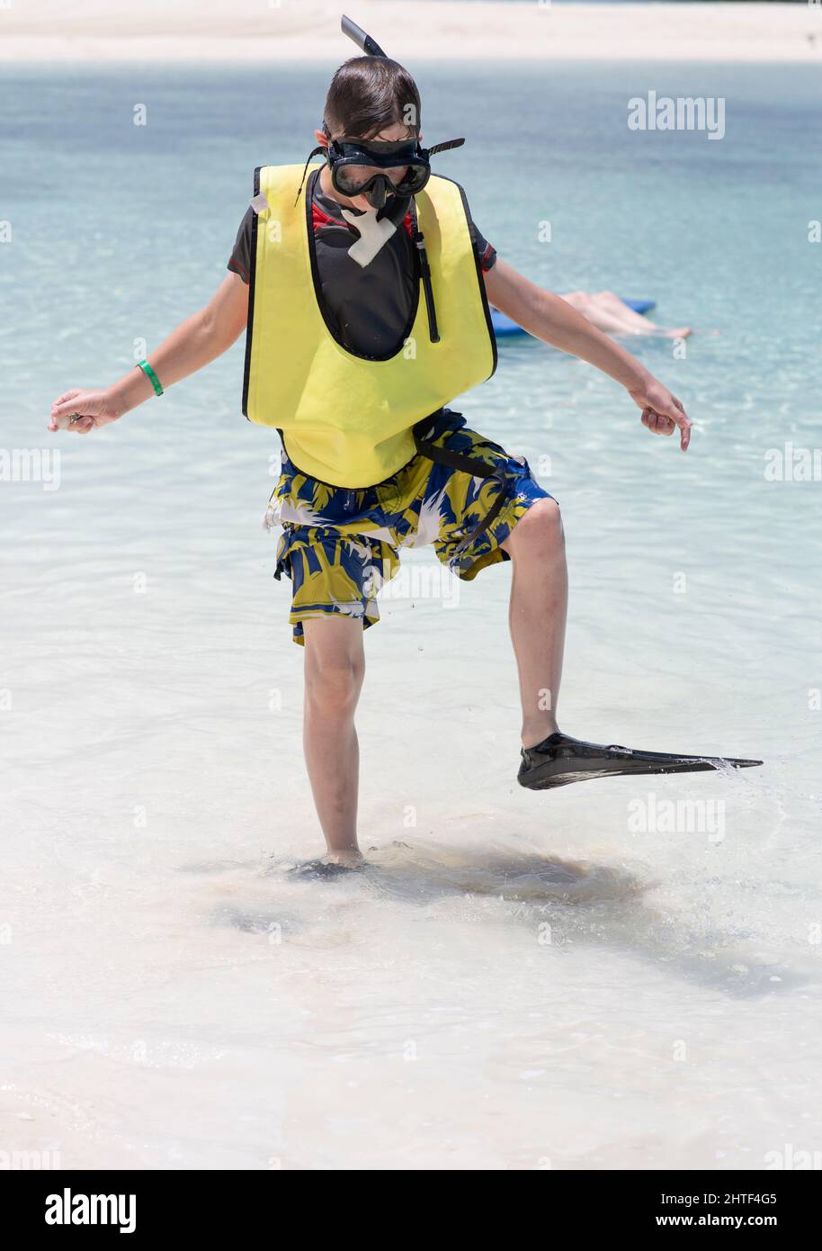 Kleiner Junge, der mit Schnorchelausrüstung in Flossen im seichten Wasser läuft Stockfoto