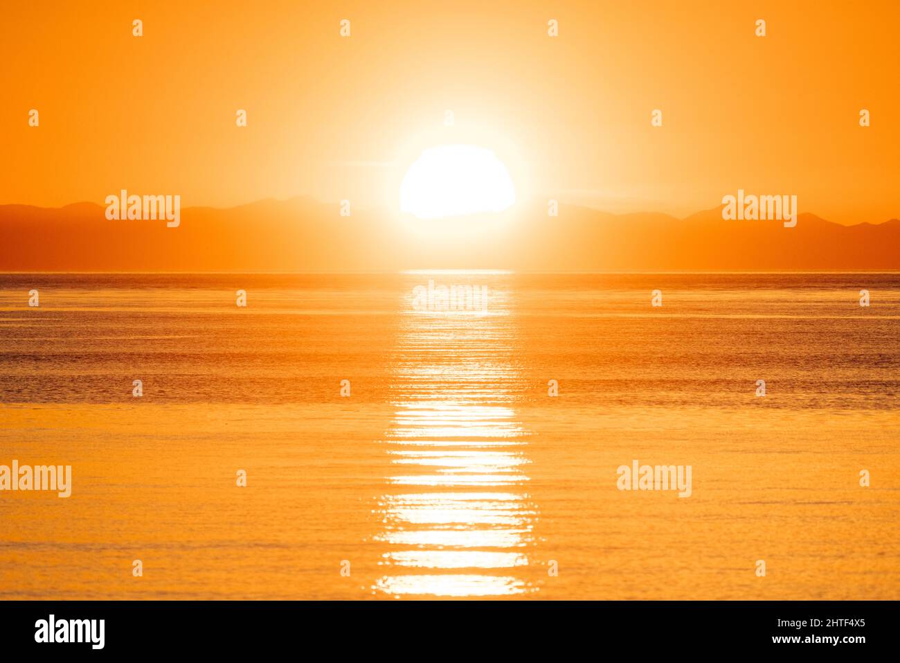 Orangefarbener Sonnenuntergang über den Olympic Mountains und dem Salishen Meer Stockfoto