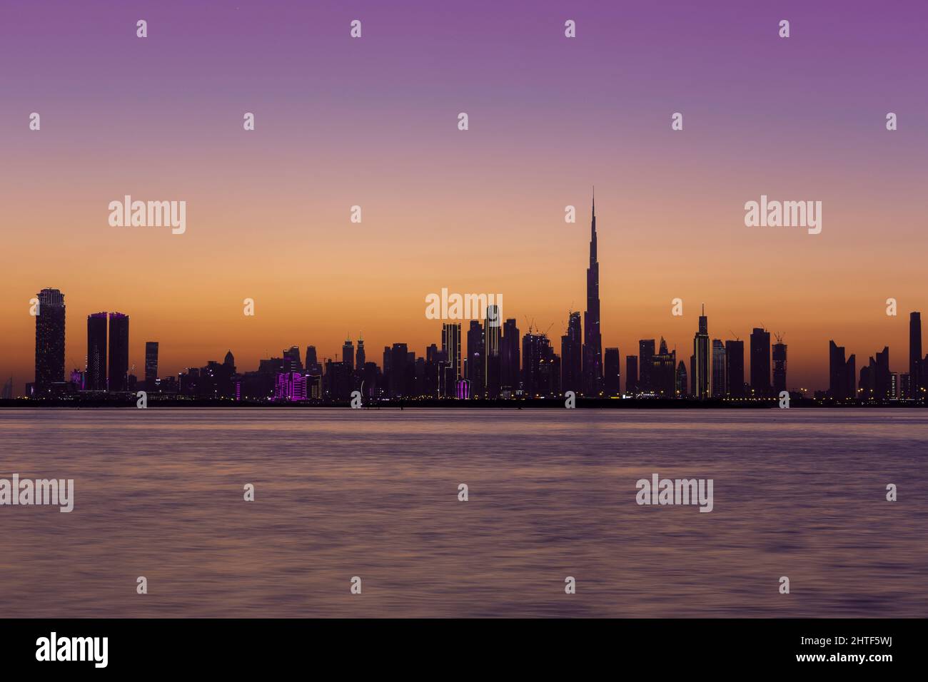 Skyline von Dubai Downtown nach Sonnenuntergang während der goldenen Stunde mit purpurem Himmel und Dubai Creek Canal, Langzeitbelichtung. Stockfoto