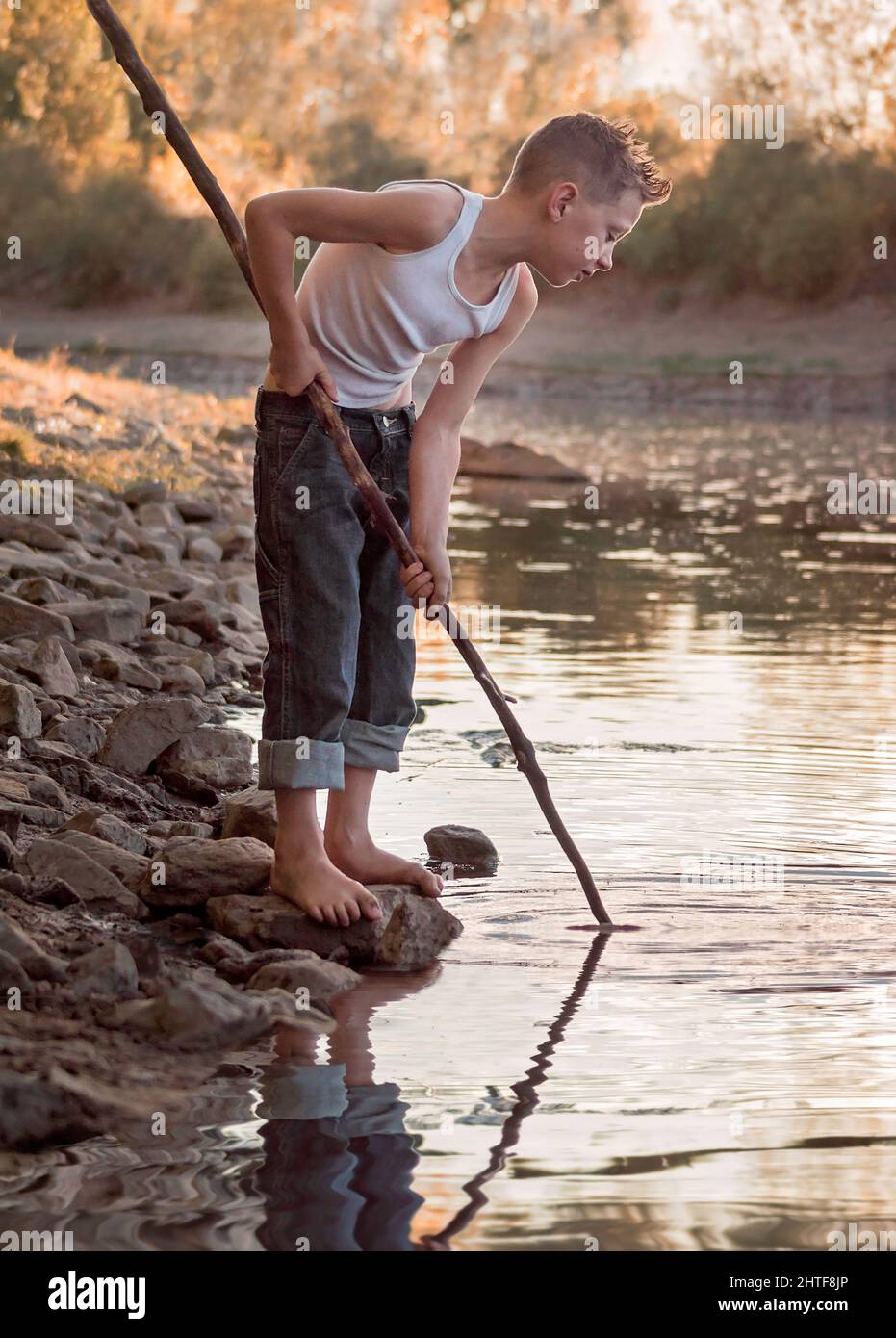 Kleiner Junge, der auf einem Flussufer spielt Stockfoto