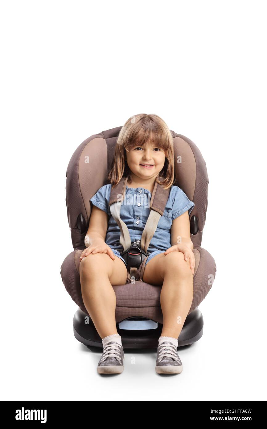 Lächelndes 4-jähriges Mädchen, das auf einem Autositz auf weißem Hintergrund sitzt Stockfoto
