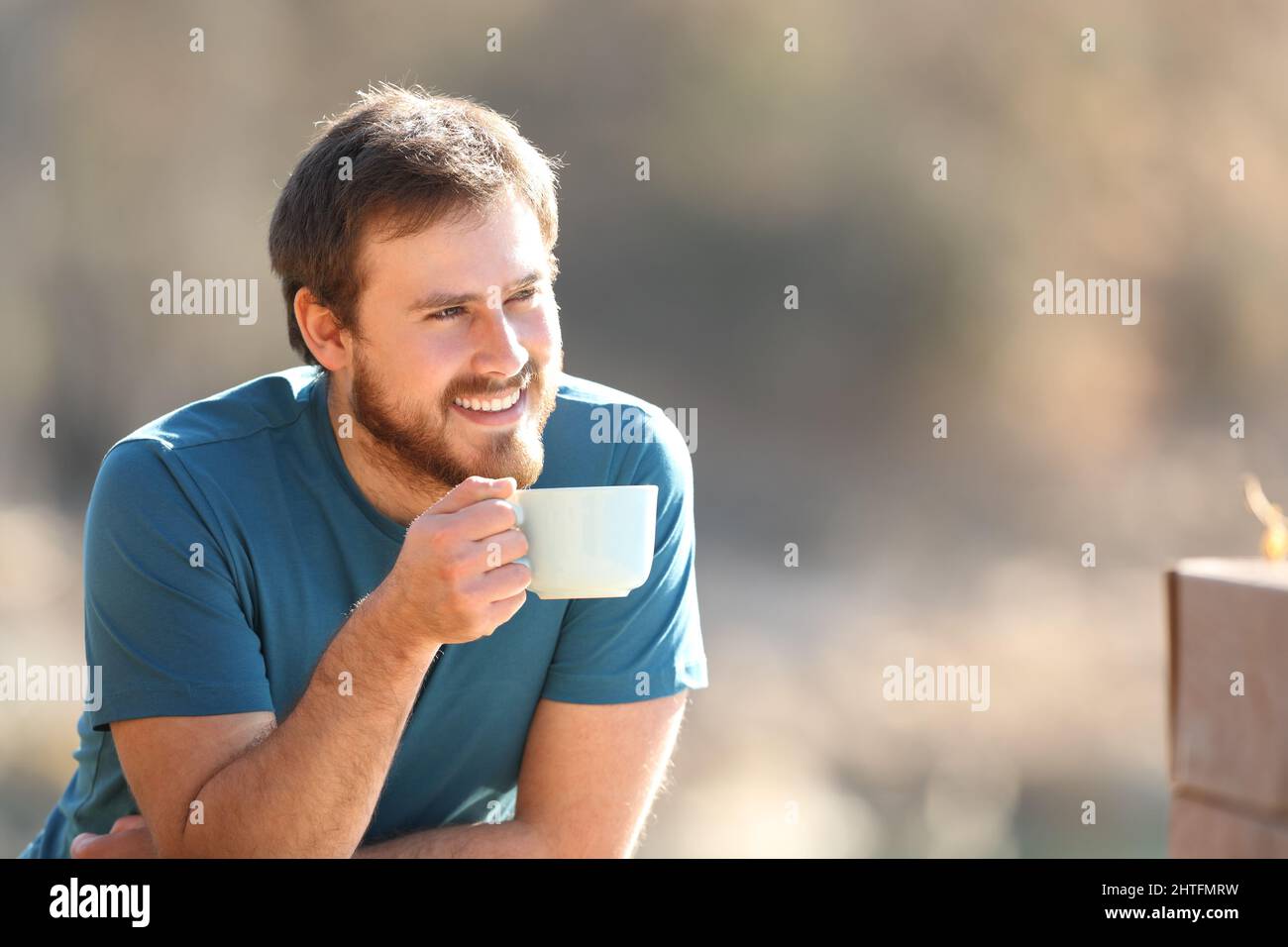 Glücklicher Mann, der Kaffee trinkt und die Aussicht im Freien in der Natur betrachtet Stockfoto