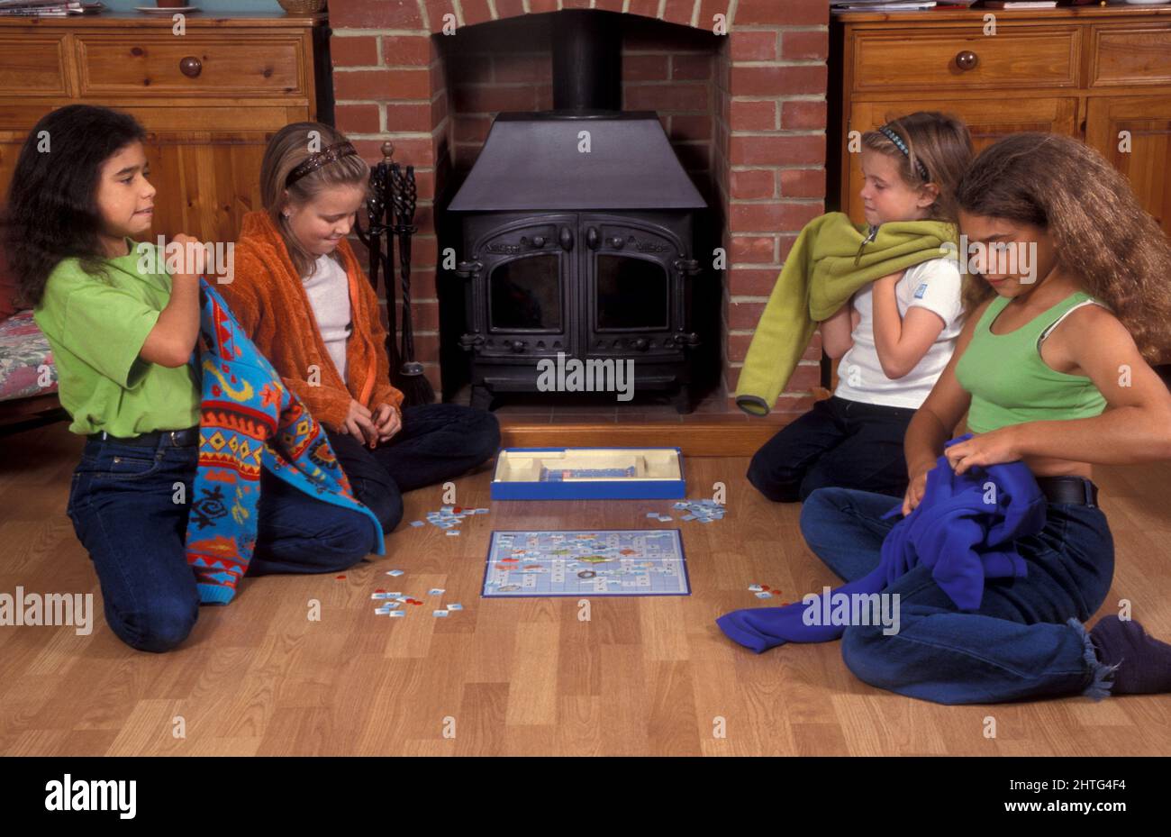 Kinder sitzen am Kamin, spielen ein Spiel und ziehen Pullover an, um Strom zu sparen Stockfoto