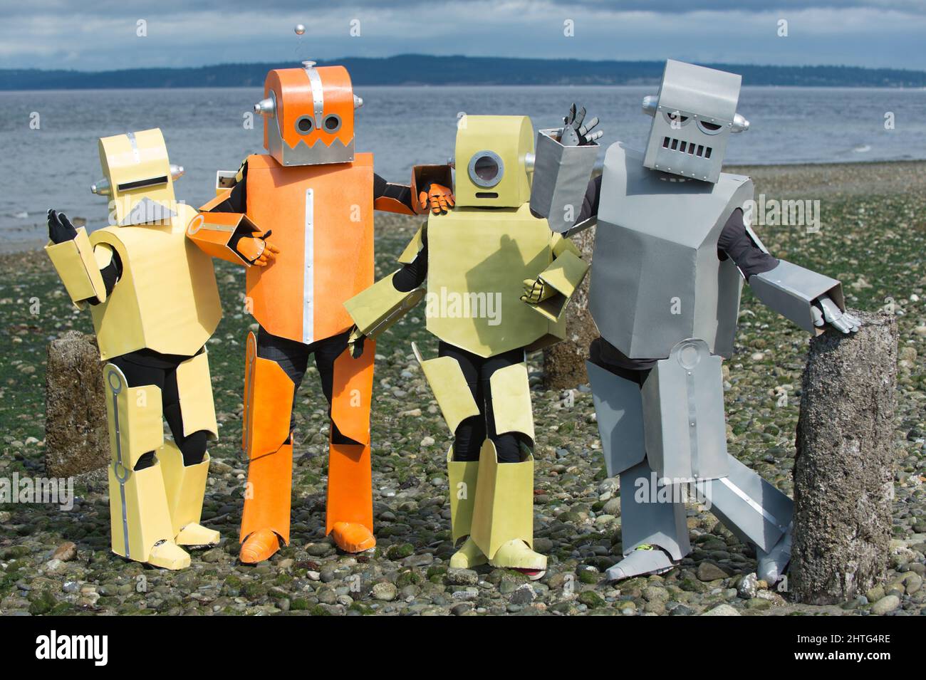 Familie von bunten Robotern posiert für ein Bild am Strand. Roboter haben Spaß. Roboter posieren und genießen ihre Fotosession. Stockfoto