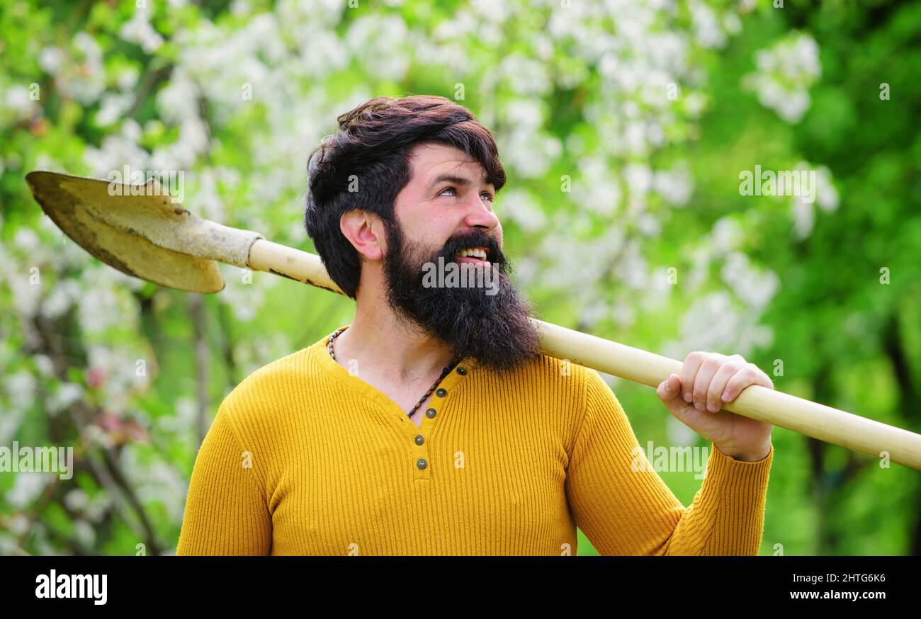 Lächelnder Gärtner mit Spaten. Bauer mit Schaufel im Garten arbeiten. Federarbeiten. Pflanzen. Stockfoto