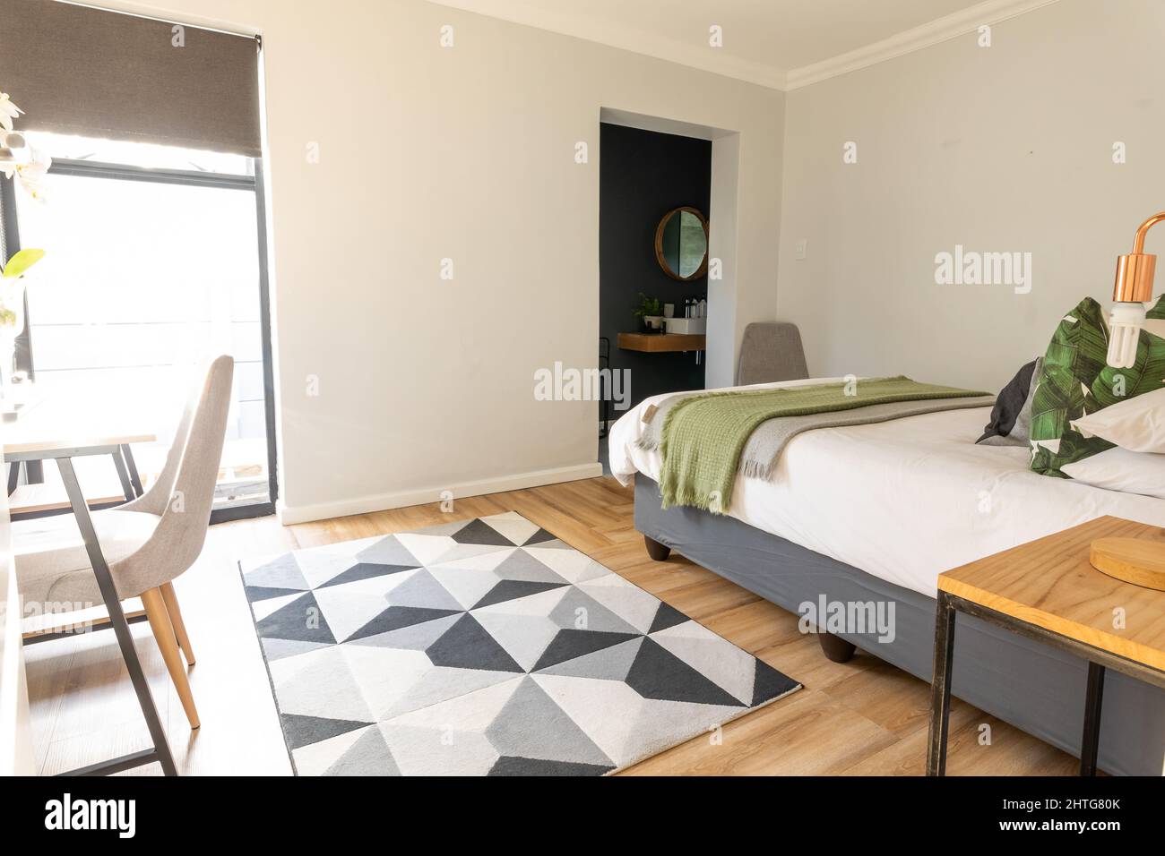Bett und gemusterter Teppich im Schlafzimmer mit Möbeln, Kopierer Stockfoto