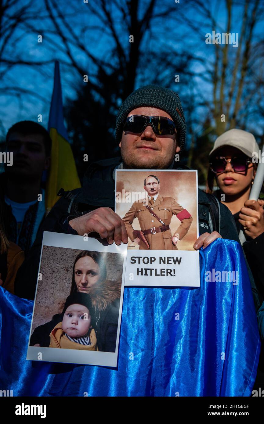 Den Haag, Niederlande. 28.. Februar 2022. Ein Protestler hält ein Plakat mit einem Bild Putins als Hitler während einer Demonstration gegen die russische Invasion der Ukraine und des russischen Präsidenten, Putin.die ukrainische Gemeinschaft in den Niederlanden protestiert am selben Tag, an dem das niederländische parlament vor dem Repräsentantenhaus über die russische Invasion in der Ukraine diskutiert, gegen Putin und den Krieg in der Ukraine. Das ukrainische Volk fordert von der niederländischen Regierung Hilfe, um Putin und seine Armee zu stoppen. Kredit: SOPA Images Limited/Alamy Live Nachrichten Stockfoto