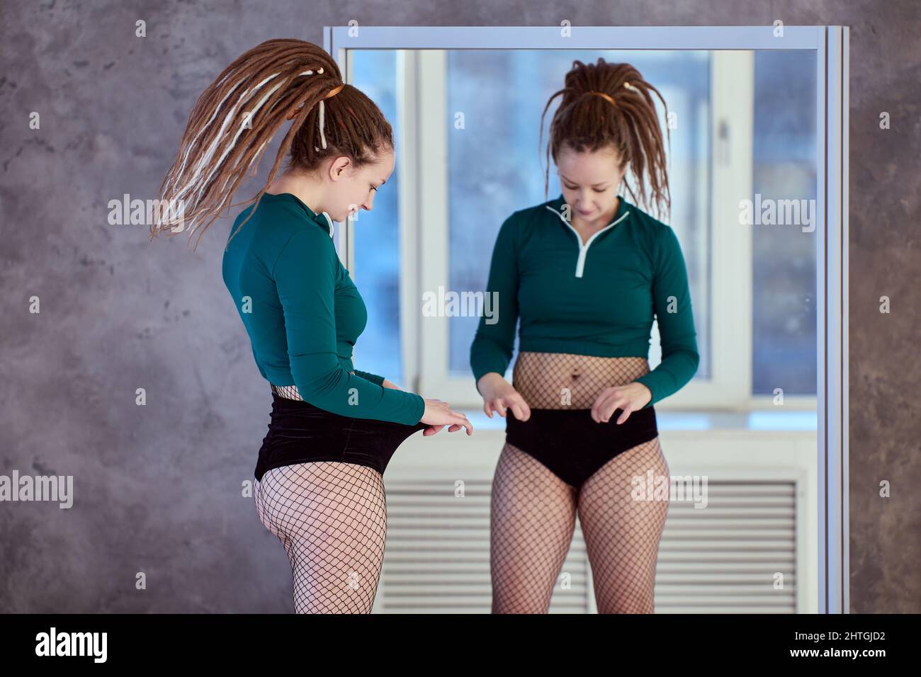 Subkutanes Bauchfett einer 28-jährigen Frau, die vor der Fitness in der Nähe des Spiegels steht. Stockfoto