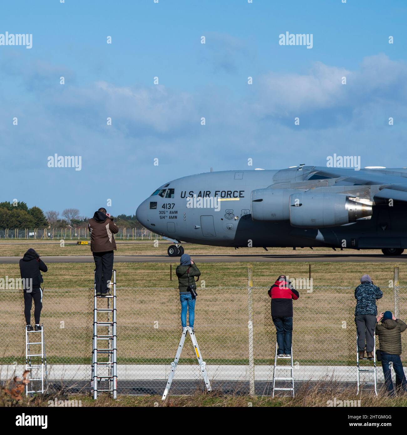 Flugzeugbeobachter auf dem Flugfeld von Mildehall machen Fotos von der Boeing C-17 Globemaster III Taxi-ing Stockfoto