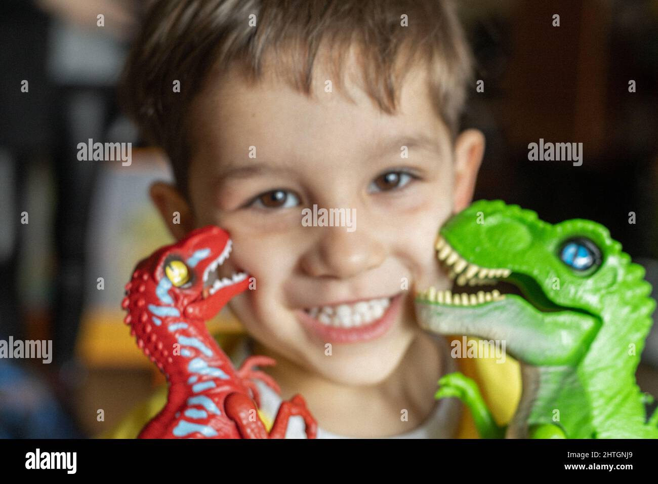 Porträt eines lächelnden Kindes, das von zwei Dinosauriern mit selektivem Fokus geküsst wird Stockfoto